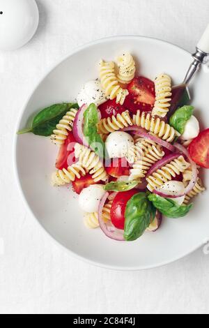 Caprese Nudelsalat mit Tomaten, Mozzarella-Käse, Basilikum. Stockfoto