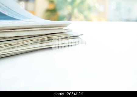 Stapel frischer Morgenzeitungen auf dem Tisch im Büro. Gefaltete und gestapelte Journale Stockfoto