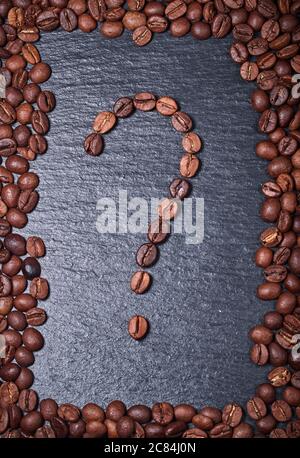 Geröstete Kaffeebohnen in Form eines Fragezeichens auf schwarzem Hintergrund Stockfoto