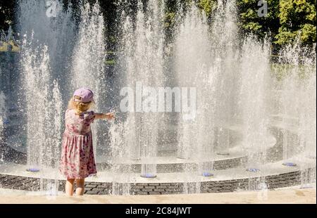 Kinder spielen im Wasser Splashing Brunnen im öffentlichen Park, Spaß an warmen sonnigen Sommertag. Stockfoto