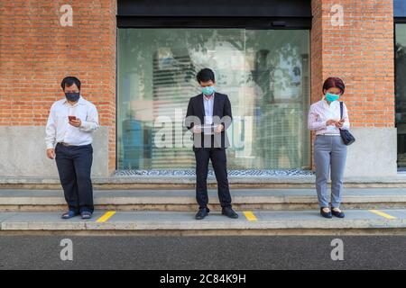 Asiatische Menschen mittleren Alters tragen Maske und halten soziale Distanzierung, um die Ausbreitung von COVID-19 zu vermeiden Stockfoto