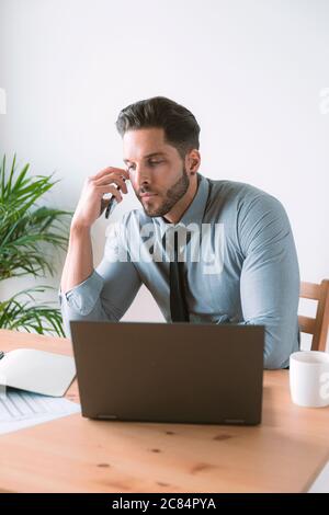 Junger Geschäftsmann, der in seinem Büro arbeitet und Kaffee trinkt Stockfoto