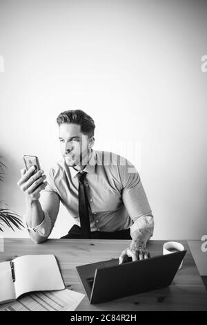 Junger Geschäftsmann, der in seinem Büro arbeitet und Kaffee trinkt Stockfoto