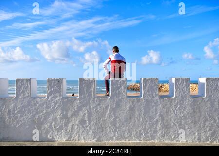 Marokko, Asilah: Badeort an der Nordwestspitze der Atlantikküste, südlich von Tanger. Mann von hinten gesehen, mit Blick auf das Meer, Blick auf die h Stockfoto