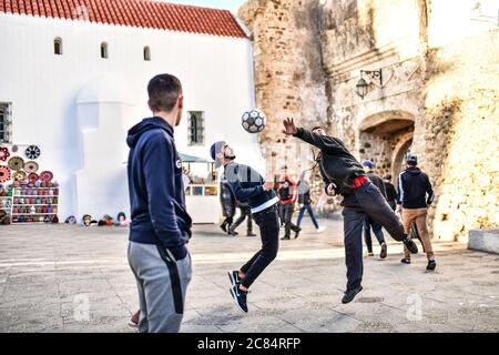 Marokko, Asilah: Badeort an der Nordwestspitze der Atlantikküste, südlich von Tanger. Gruppe junger Menschen, die auf einem Stadtplatz Fußball spielen Stockfoto