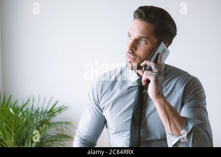 Junger Geschäftsmann, der in seinem Büro arbeitet und Kaffee trinkt Stockfoto