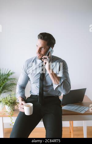 Junger Geschäftsmann, der in seinem Büro arbeitet und Kaffee trinkt Stockfoto