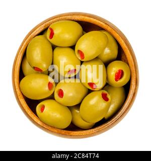 Paprika gefüllte grüne Oliven in Holzschüssel. Große europäische Oliven, Früchte von Olea europaea, gefüllt mit eingelegten roten Paprikascheiben. Stockfoto
