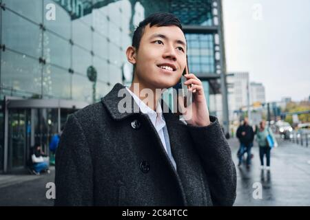 Junge attraktive asiatische Geschäftsmann glücklich im Gespräch auf Smartphone Stockfoto