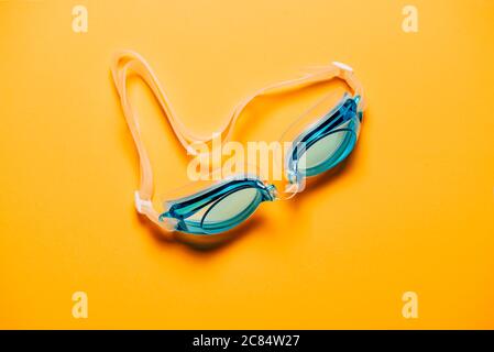 Blaue Schwimmbrille, mit Gummiband auf gelbem Hintergrund. Niemand, Produktkonzept Stockfoto