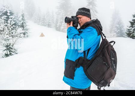 Ein Mann macht Bilder von etwas oder jemand in einem verschneiten Wald stehen. Schöne Winternatur. Fotograf im verschneiten Wald Stockfoto