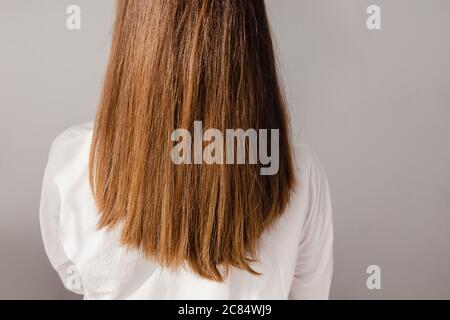 Rückansicht der jungen Frau in weißem Hemd mit langen schönen glänzenden hören. Stockfoto