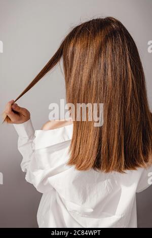 Rückansicht der jungen Frau in weißem Hemd mit langen schönen glänzenden hören. Stockfoto