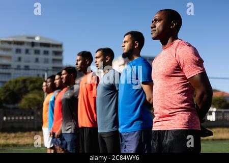 Multi ethnische Gruppe von männlichen fünf ein Seite Fußballspieler tragen Sportkleidung Training auf einem Sportplatz in der Sonne, in einer Reihe vor einem Spiel stehen. Stockfoto