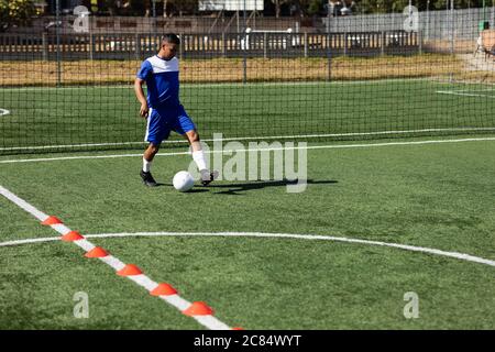 Gemischtes Rennen männlich fünf ein Nebenfußballspieler trägt eine Mannschaftsstreifen Training auf einem Sportplatz in der Sonne, Aufwärmen Tackling mit Ball. Stockfoto