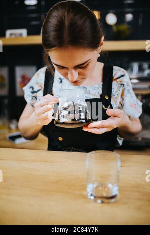 Barista Mädchen schnüffeln gebrühten Kaffee in einer Glaskanne - Tropfkaffee Zubereitung Methode Stockfoto