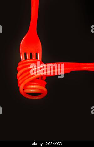 Spaghetti neu definiert. Heiße rote Spaghetti auf einer roten Gabel auf schwarzem Hintergrund Stockfoto