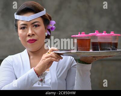 Indonesian balinesian Frau trägt ein Tablett mit süßen Getränken während einer religiösen Hindu-Tempel Zeremonie (Odalan Festival) und Posen für die Kamera. Stockfoto