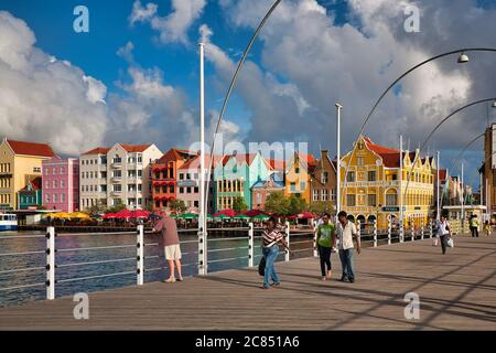 Menschen, die über die Queen Emma Brücke mit typisch holländischen Gebäuden im Hintergrund, Willemstat, Curacao, Karibik, West Indies Stockfoto