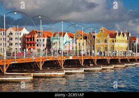 Menschen, die über die Queen Emma Brücke mit typisch holländischen Gebäuden im Hintergrund, Willemstat, Curacao, Karibik, West Indies Stockfoto