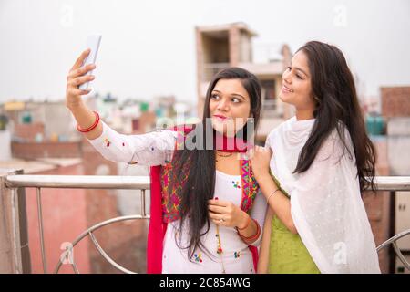 Schöne indische junge Frauen nehmen Selfie zusammen über Smartphone in frischer Luft und verbringen ihre Freizeit am Tag Zeit. Stockfoto