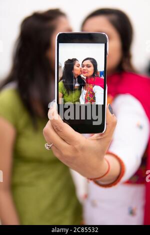 Schöne, glückliche indische junge Frauen nehmen Selfie zusammen über Smartphone Sie tragen ihr traditionelles Kleid Salwar Kameez und Dupatta. Stockfoto