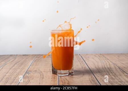 Orangensaft wird aus einem Glas gesprüht. Sprühen Sie ein süßes Getränk. Ein Spritzer Fruchtsaft. Stockfoto