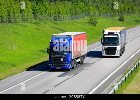 Weißer Volvo FH Sattelanhänger überholt blauen Scania Sattelschlepper mit schwerer Last. Salo, Finnland. Juni 12, 2020. Stockfoto