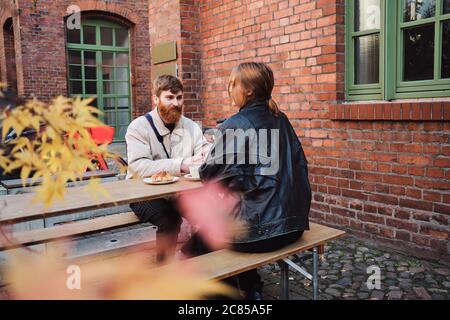 Junger Mann, der seine Freundin gerne auf dem Date im Straßencafé ansah Stockfoto