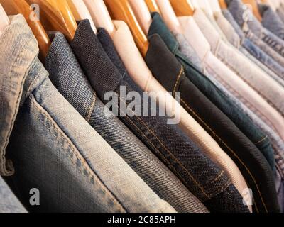 Eine Auswahl an Jeansjacken, die an einer Schiene hängen, illustrieren die verschiedenen Töne und Texturen des verfügbaren jean-Stoffes Stockfoto