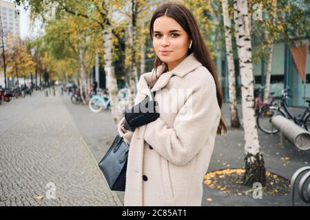 Schöne Brünette Mädchen im Mantel traumhaft suchen in der Kamera auf der Straße Stockfoto