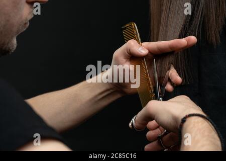 Eine Nahaufnahme der Friseurhände schneiden Haare, Friseur mit Kunden