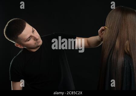 Attraktive junge Haar Dresser Kämmen Kunden Haar im Salon Stockfoto