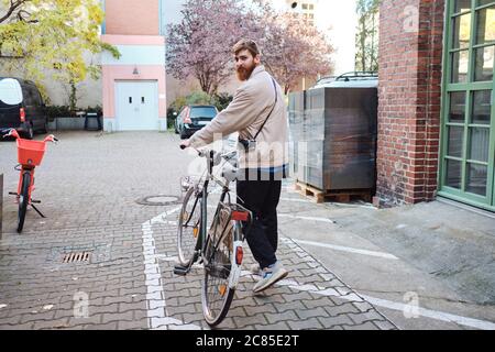 Junge attraktive Casual Mann zu Fuß durch die Straße mit klassischen Fahrrad Stockfoto