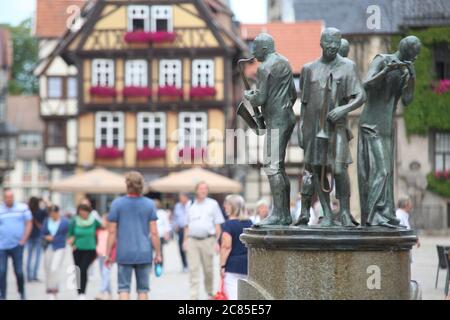 Quedlinburg, Deutschland. Juli 2020. Auf dem Marktplatz in Quedlinburg spazieren die Menschen. Die Münzenberg-Musiker, eine aus vier Figuren bestehende Bronzeskulptur des Quedlinburger Künstlers Wolfgang Dreysse, sind auf dem Marktplatz in der Altstadt von Quedlinburg zu sehen. Quelle: Matthias Bein/dpa-Zentralbild/ZB/dpa/Alamy Live News Stockfoto