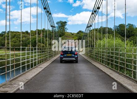 River Tweed, Englisch/Schottische Grenze, Großbritannien, 21. Juli 2020. 200 Jahre Union Bridge: Die Brücke feiert am 26. Juli ihr 200-jähriges Bestehen. Es war die erste Fahrzeugaufhängung Brücke in Großbritannien. Zur Zeit ihrer Errichtung war sie mit 137 m die längste schmiedeeiserne Hängebrücke der Welt. Es wird immer noch regelmäßig von Fußgängern, Radfahrern und Autos verwendet, aber Autos müssen es zu einer Zeit überqueren. Diese Ansicht ist von der schottischen Grenze. Ein Skoda Yeti Auto überquert die Brücke Stockfoto