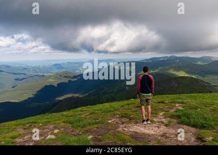 Reisender steht auf hohen Bergklippen, genießen Landschaft auf Berggipfel. Pov-Ansicht. Konzept der Freiheit beim Wandern Stockfoto