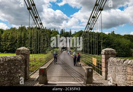 River Tweed, Englisch/Schottische Grenze, Großbritannien, 21. Juli 2020. 200 Jahre Union Bridge: Die Brücke feiert am 26. Juli ihr 200-jähriges Bestehen. Es war die erste Fahrzeugaufhängung Brücke in Großbritannien. Zur Zeit ihrer Errichtung war sie mit 137 m die längste schmiedeeiserne Hängebrücke der Welt. Es wird immer noch regelmäßig von Fußgängern, Radfahrern und Autos verwendet, aber Autos müssen es zu einer Zeit überqueren. Diese Ansicht ist von der englischen Grenze. Die Leute gehen über die Brücke Stockfoto