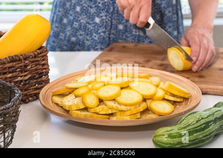 Gelbe und grüne Zucchini auf Küchentisch. Frau Zucchini close up auf Holzbrett auf weißem Küchentisch schneiden Stockfoto