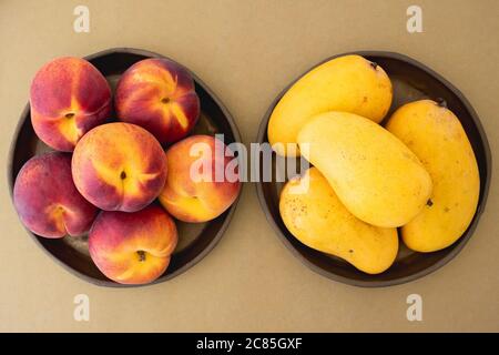 Pfirsiche und Mangos auf Platten aus der Nähe, Blick von oben Stockfoto