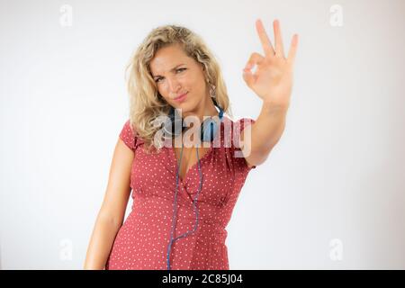 Hübsche blonde Frau in rotem Kleid mit Kopfhörern Stockfoto