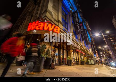 Philadelphia, PA - 4. Februar 2020; Zeitbelichtung erfasst unscharfe Bewegungen von Kunden, die in die und aus der Eingangstür des Wawa-Lebensmittelladens in der Innenstadt kommen Stockfoto
