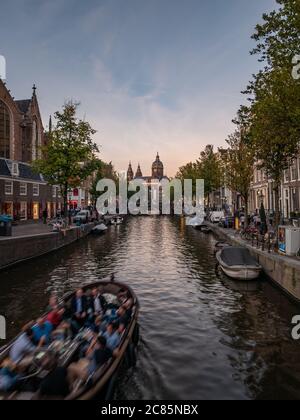 Amsterdam, Niederlande - Oktober 15 2018: Ein Blick am frühen Abend auf einen der Kanäle im Zentrum von Amsterdam, während Boote unter einer Brücke passieren. Stockfoto