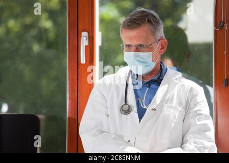 Porträt eines müden oder erschöpften Arztes, der in einem hellen Wartezimmer eines Krankenhauses oder einer Klinik sitzt - Fokus auf das Gesicht Stockfoto