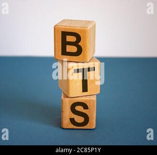 Holzwürfel mit der Aufschrift 'BTS'. Schöner blauer Tisch und weißer Hintergrund, Kopierraum. Stockfoto