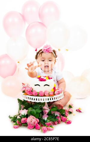 Vertikale Lifestyle-Porträt eines Babys mit einem Kuchen zerschlagen, um ihren ersten Geburtstag zu feiern. Stockfoto