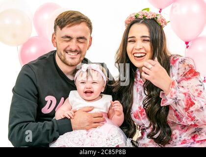 Horizontales Lifestyle-Porträt einer jungen Familie zum ersten Geburtstag ihrer Tochter. Stockfoto