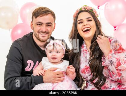 Horizontales Lifestyle-Porträt einer jungen Familie zum ersten Geburtstag ihrer Tochter. Stockfoto