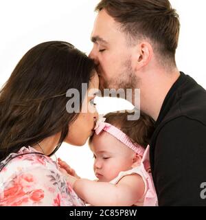 Quadratisches Lifestyle-Porträt eines jungen Paares mit ihrer Tochter an ihrem ersten Geburtstag. Stockfoto