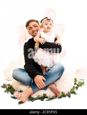 Vertikales Lifestyle-Porträt eines jungen Vaters mit seiner kleinen Tochter an ihrem ersten Geburtstag. Stockfoto